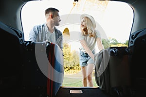 Couple putting suitcases in car trunk for a journey