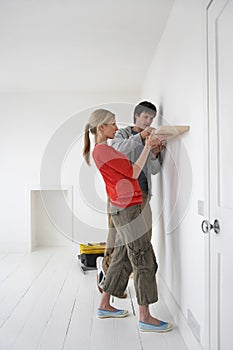 Couple Putting Up Shelf In New Home