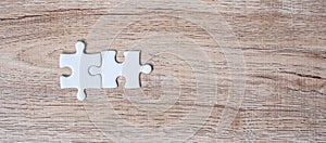 Couple puzzle pieces on wood table background. Business solutions, mission target, successful, goals, cooperation, partnership and