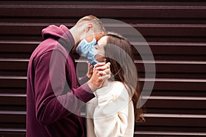 Couple in quarantine trying to kiss wearing a mask . Focus on hands