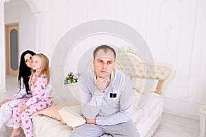 Couple quarrel and child upset, sitting bed in white interior