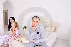 Couple quarrel and child upset, sitting bed in white interior
