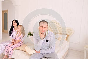 Couple quarrel and child upset, sitting bed in white interior