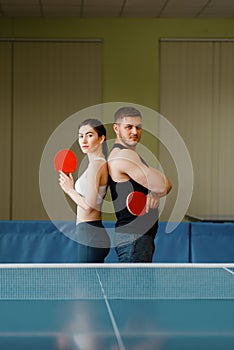 Couple with rackets poses at the ping pong table