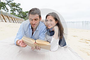 couple reading book on beach