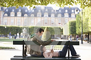 Couple Reading Book On Park Bench