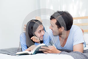 Couple reading a book together in bedroom on the morning.