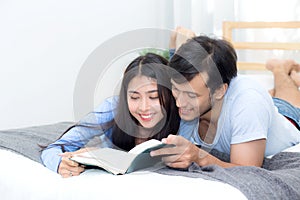 Couple reading a book together in bedroom on the morning with happiness.