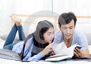 Couple reading a book together in bedroom on the morning.