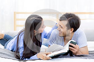 Couple reading a book together in bedroom on the morning with happiness.