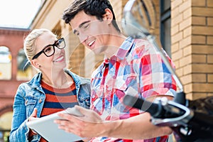 Couple reading city guide before making scooter tour in Berlin