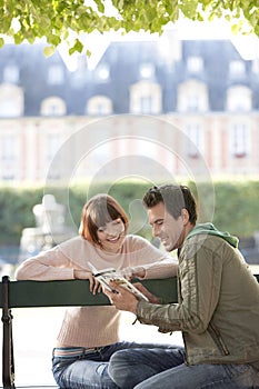 Couple Reading Guide Book On Park Bench