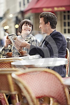 Couple Reading Guidebook At Outdoor Cafe