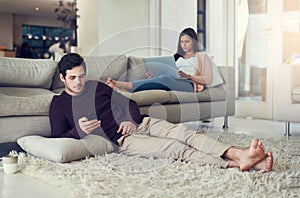 Couple, reading and relax in living room with phone, laptop and social media notification on mobile app in home. Man