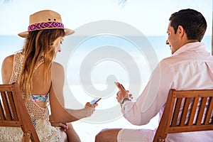 Couple reading social media at the beach