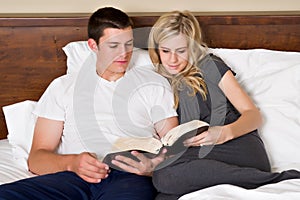 Couple reads the Bible in bed
