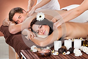 Couple receiving shoulder massage at spa