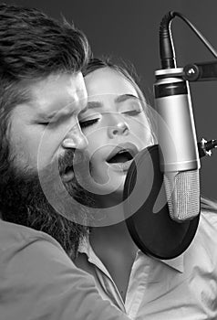 Couple in recording studio. Music performance vocal. Singer singing song with a microphone.