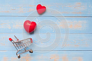 couple red heart shape with mini shopping cart on blue pastel wooden table. love, shopping and Valentine Day Concept