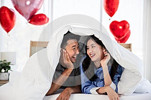 Couple with red rose flower, lovely couple lying in a bed, happy smile kissing, concept of valentine day