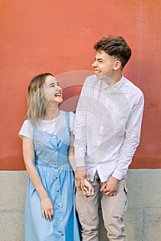 Couple, relationships, outdoor portrait. Stylish hipster happy couple, guy in white shirt and girl in blue dress, having