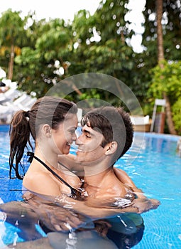 Couple, relax in pool and hug outdoor, love and connection with summer vacation at resort or hotel. Happy people