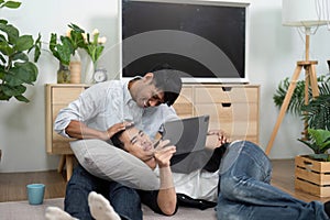 Affection and Relaxation. Two men enjoying a cozy moment while using a tablet at home. photo