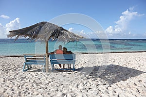 A couple relaxes under a rustic umbrella on Anegada in the British Virgin Islands