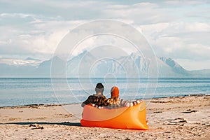 Couple relaxing in air lounger on beach enjoying sea and mountains view