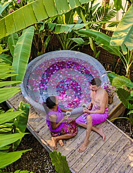 Couple relaxing in a bathtub in the rainforest of Thailand during vacation with flowers in the bath