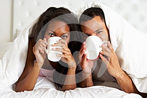 Couple Relaxing In Bed With Hot Drink