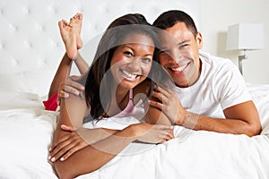 Couple Relaxing In Bed Wearing Pajamas