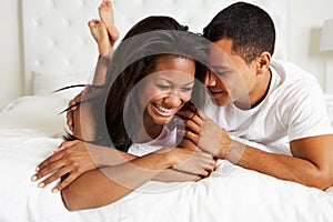 Couple Relaxing In Bed Wearing Pajamas