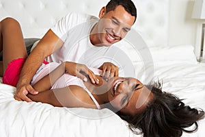 Couple Relaxing In Bed Wearing Pajamas