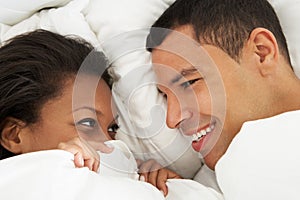 Couple Relaxing In Bed Wearing Pajamas