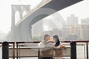 Couple Relaxing On Bench Under Brooklyn Bridge
