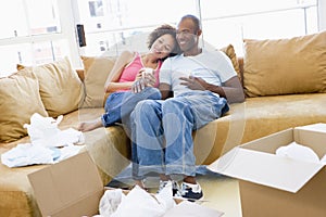 Couple relaxing with coffee by boxes in new home