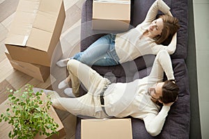 Couple relaxing on couch moving into new home with boxes