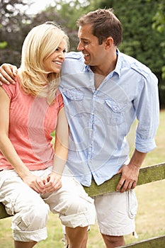 Couple Relaxing In Countryside Sitting On Fence