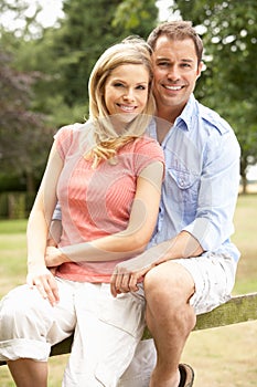 Couple Relaxing In Countryside Sitting On Fence