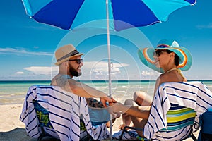 Couple relaxing on a deck chairs on a beach