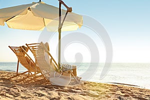 Couple relaxing on deck chairs at beach. Summer vacation