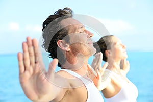 Couple relaxing and doing yoga on the shore