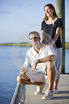 Couple relaxing with drink on dock by water