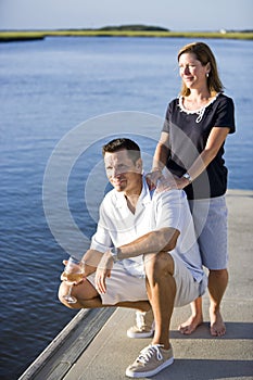 Couple relaxing with drink on dock by water