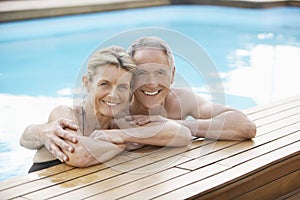 Couple Relaxing On The Edge Of Swimming Pool