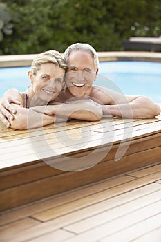 Couple Relaxing On The Edge Of Swimming Pool