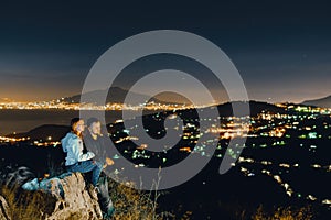 Couple relaxing enjoy view from the top of the mountain to the lights of the city of Sorrento. Volcano Vesuvio. Sea and romance.