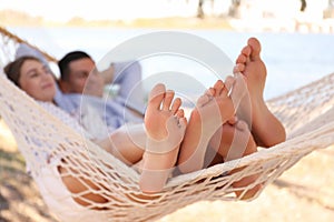 Couple relaxing in hammock on beach, focus on legs