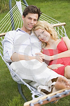 Couple relaxing in hammock smiling